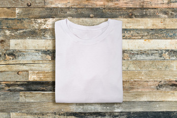 Blank white folded t-shirt on wooden vintage background
