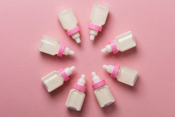 Baby bottles with milk on a pastel pink background