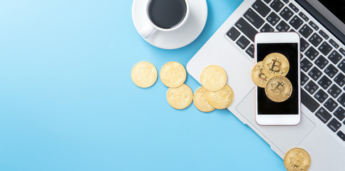 Stylized clean blue office working desk with bitcoin, smartphone, laptop and coffee cup, workspace design, mock up, top view, flat lay, copy space, close up