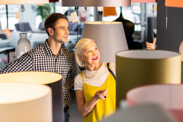 Delightful elderly madam paying boyfriend attention to lamp she liked