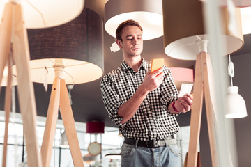 Attractive tall male customer making price-tag photo on the phone