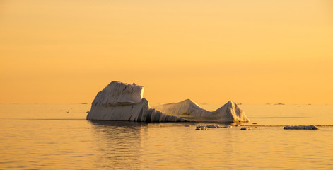Icebergs floating in the ocean during sunset midnight sun in the Ilulissat Icefjord in Greenland.