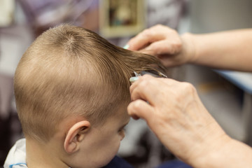 Obraz na płótnie Canvas Little boy does a haircut at the hairdresser. Baby hair care.