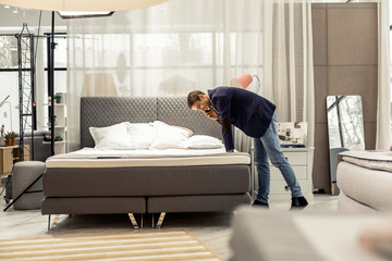 Attractive mature man consulting via phone about new bed purchasing