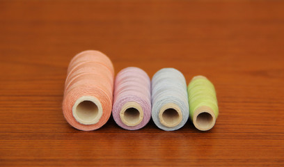 four spools with purple, blue, green and ochre threads on the table