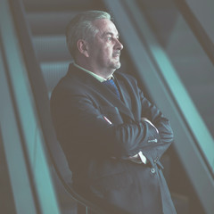 successful businessman standing on the stairs of a modern office on a dark background