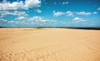 Sandy beach, yellow sand and blue sky with clouds, beautiful summer landscape for background..