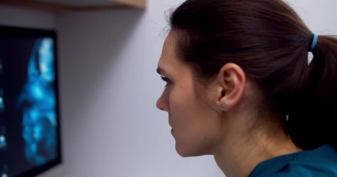 Professional female doctor neurologist working with brain MRI scans on a computer at her personal desk at hospital. 4K UHD