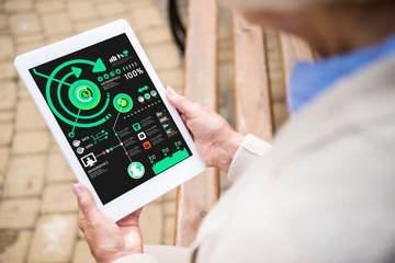 selective focus of senior woman holding laptop with inforgraphics on screen