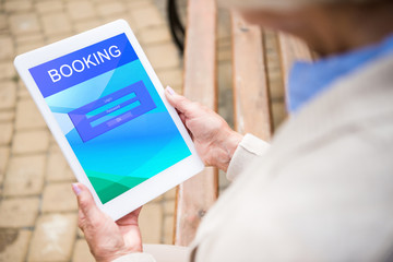 selective focus of senior woman using digital laptop with booking on screen