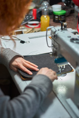 Fototapeta na wymiar The hand of a designer who stitching a fragment of a bag