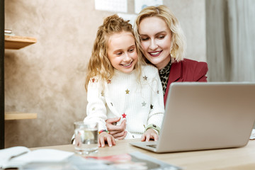 Good-looking adult mother with wide smile carrying her daughter