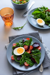 Salad mix with spinach, arugula,beet leaves, tomatoes and eggs on gray wooden background. Vegetarian food concept. Selective focus.