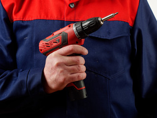 man in workwear holds a drill tool on white background.