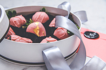 Chocolate-covered strawberries in a gift box with a transparent lid and a gray ribbon and envelope with sealing wax