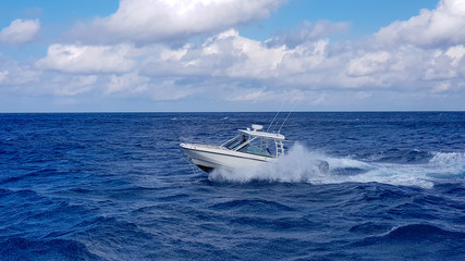 Speed fishing tender boat jumping the waves in the sea and cruising the blue ocean day in Bahamas. Blue beautiful water - obrazy, fototapety, plakaty
