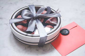Chocolate-covered strawberries in a gift box with a transparent lid and a gray ribbon and envelope...