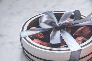 Chocolate-covered strawberries in a gift box with a transparent lid and a gray ribbon and envelope...