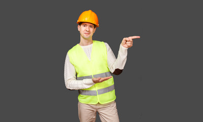 The man the builder in a helmet and a vest points a finger aside sideways