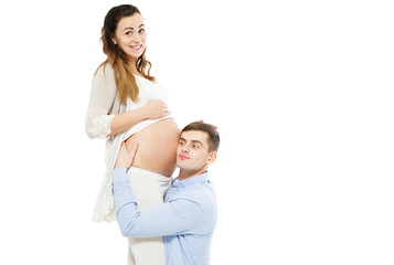 Fototapeta premium Young attractive couple: pregnant mother and happy father who listening pregnant belly