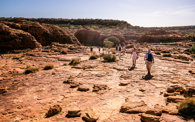 Caucasian people walking under a blazing sun during Rim walking trail at Kings Canyon in outback...