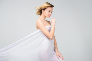 Naklejka premium elegant naked girl posing in white cloth, isolated on grey