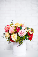 bouquet of summer flowers in round box over white wall background with copy space