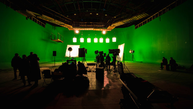 Behind the scenes or the making of film video production and movie crew team working in silhouette of camera and equipment set in studio