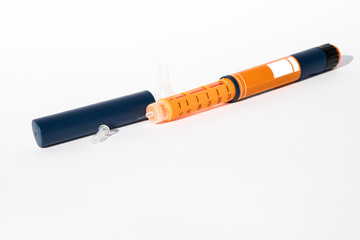Orange colored insulin injector of pen type. One time, disposable needle mounted