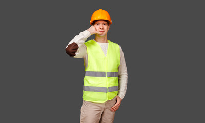 The man the builder keeps fingers of hands about an ear in a helmet and a vest and a mouth of the head