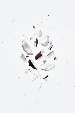 Flying pieces of coconut on white color. Exotic levitation concept for cosmetics, spa, perfume, health care products, aroma background with copy space