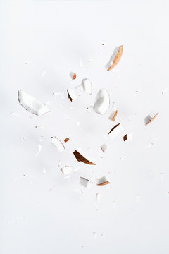 Flying pieces of coconut on white color. Exotic levitation concept for cosmetics, spa, perfume, health care products, aroma background with copy space