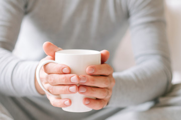 Fototapeta na wymiar Wake up beverage. Man sitting and holding white cup of hot morning tea.