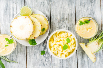 Homemade pineapple smoothie with fresh pineapple slices on wooden table, top view copy space