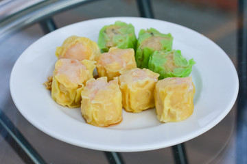 Green and yellow hot Chinese shrimp dumplings steamed in white dish for served in morning. Food and appetizer.