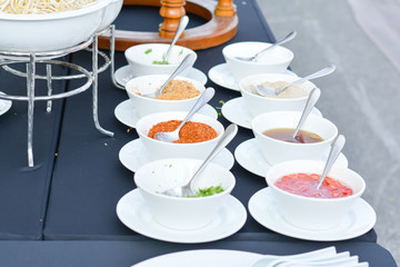 Groups of Thai seasoning (Fish salt, chili powder, sugar, salt and soy sauce) in white bowls on table for served in party. 