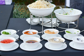 Groups of Thai seasoning (Fish salt, chili powder, sugar, salt and soy sauce) in white bowls on table for served in party. 