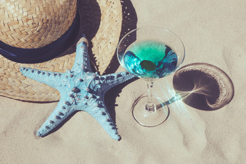 Summer refreshing cocktail straw hat and blue starfish on the sand