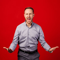 angry man screaming over red background. emotion and people concept