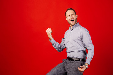 man celebrating victory over red background. emotion, gesture and people concept