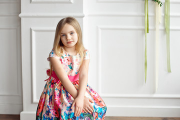 Portrait of little smiling girl child in colorful dress posing indoor.