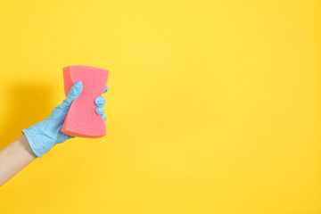 Housekeeping concept. Organized housewife. Woman hand holding sponge ready for washing up. Copy space on yellow background.