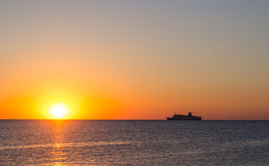 Naklejka na ściany i meble Cruise ship sailing in the sea at sunset 