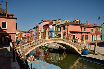 Fototapeta na wymiar Venice, Burano island canal, small colored houses and the boats. Woman tourist. Colorful concept.
