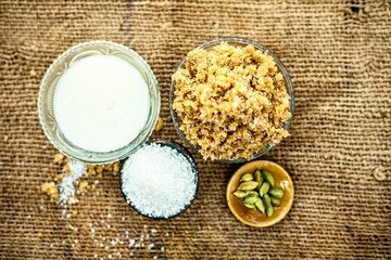 Close up of popular Indian & Asian sweet dish i.e. Malida or churma na ladu or moti chur na ladu in a bowl on brown surface with entire ingredeints including dry fruits.;