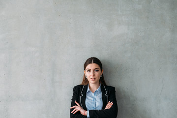 Successful corporate career. Confident business woman standing with arms crossed. Copy space on grey background.