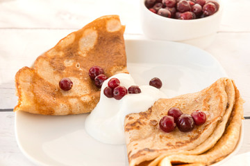 pancakes with sour cream and cranberries on a plate