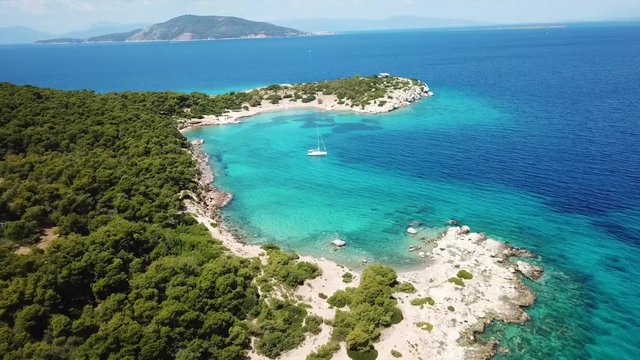 Aerial drone bird's eye view video of boat docked in paradise island of Moni next to Aegina island with emerald crystal clear waters, Saronic gulf, Greece