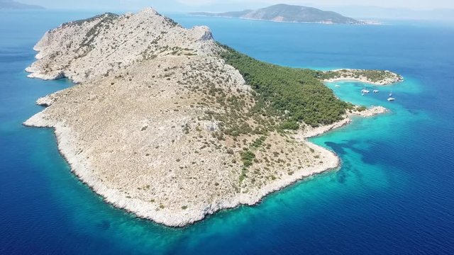 Aerial drone bird's eye view video of boat docked in paradise island of Moni next to Aegina island with emerald crystal clear waters, Saronic gulf, Greece
