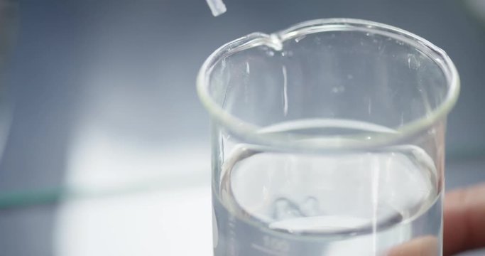 Scientist is pipetting a clear liquid in sterile laboratory